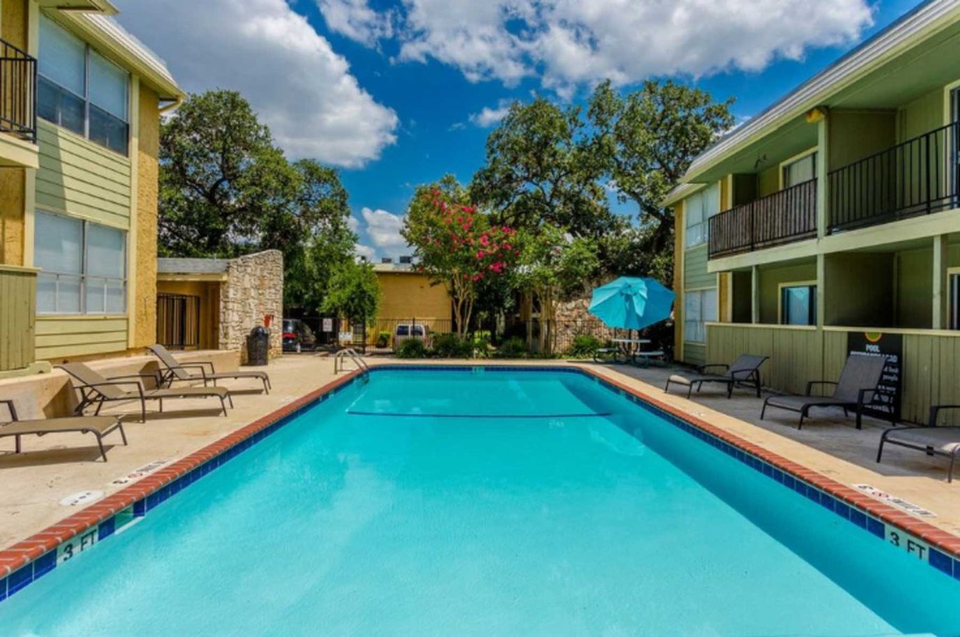 Swimming pool surrounded by lounge chairs and greenery