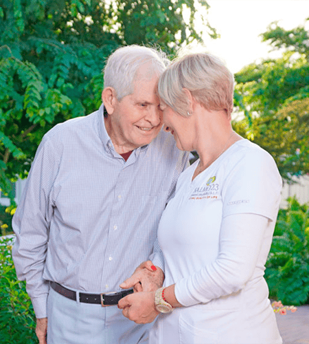 A resident smiling with a caregiver in a garden