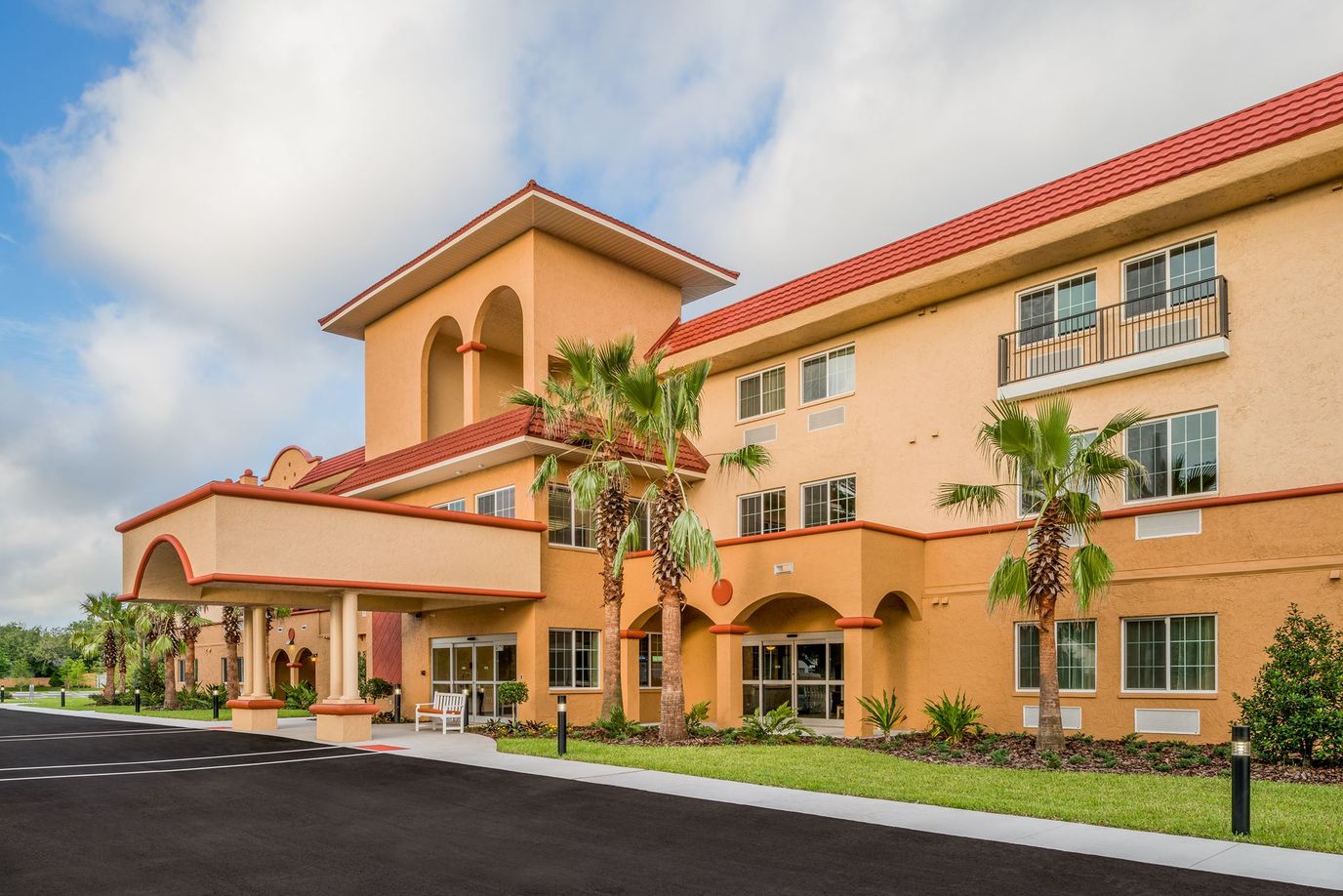 Exterior view of a senior living facility with palm trees