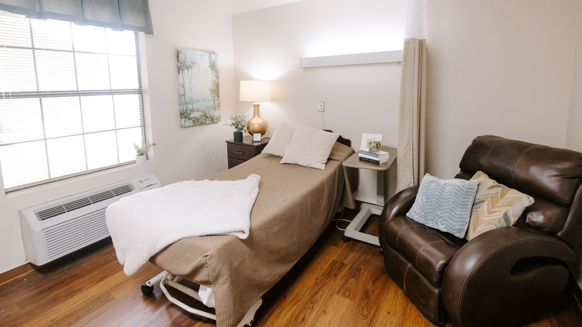 A cozy resident room with a bed and chair