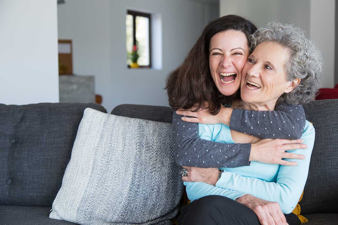 Two women laughing together on a couch