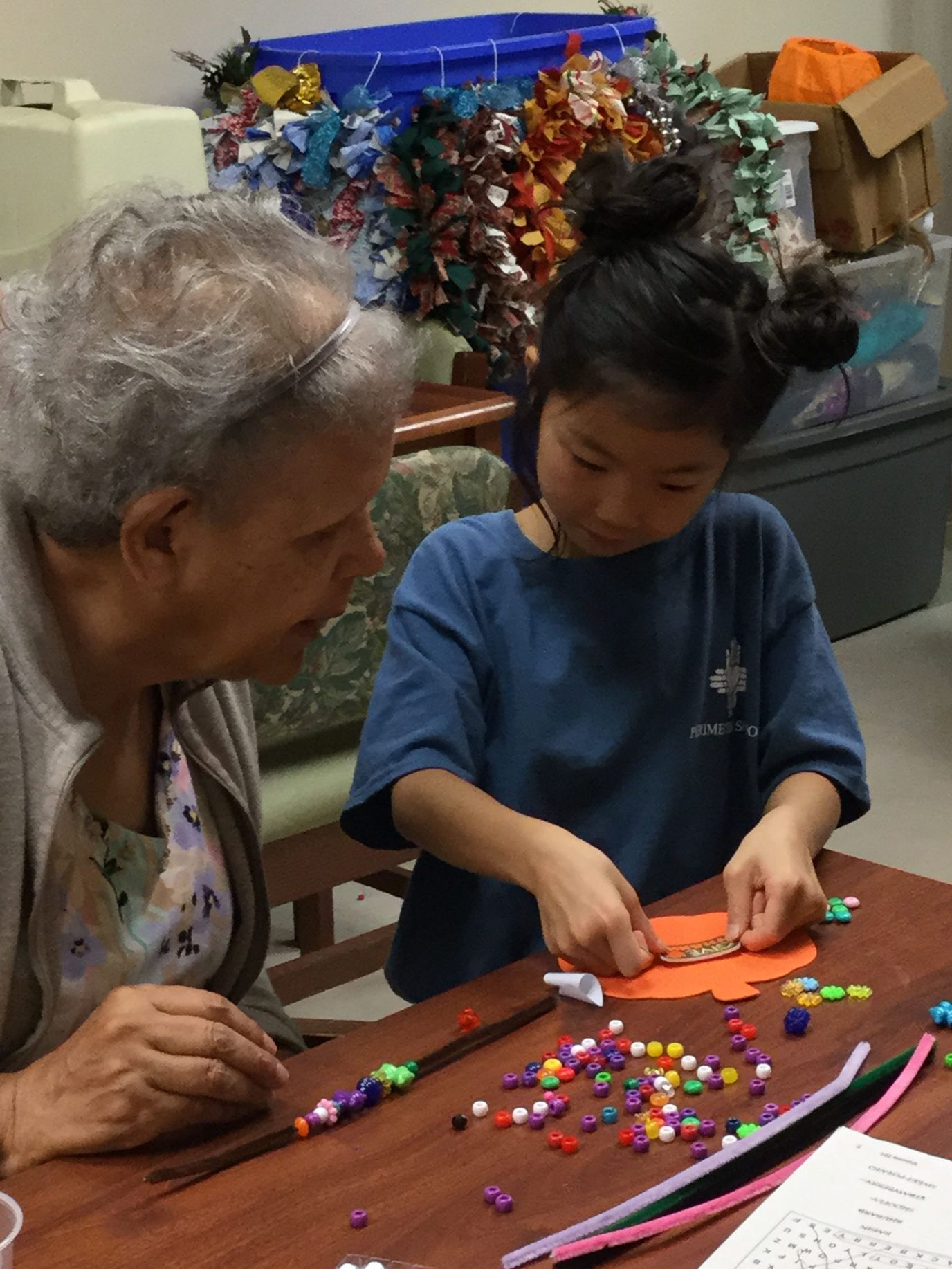 An elderly resident crafting with a child in a vibrant activity room