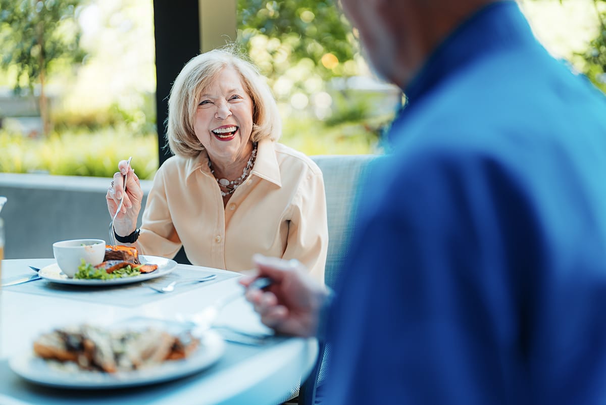 A resident enjoying lunch outdoors with a smile