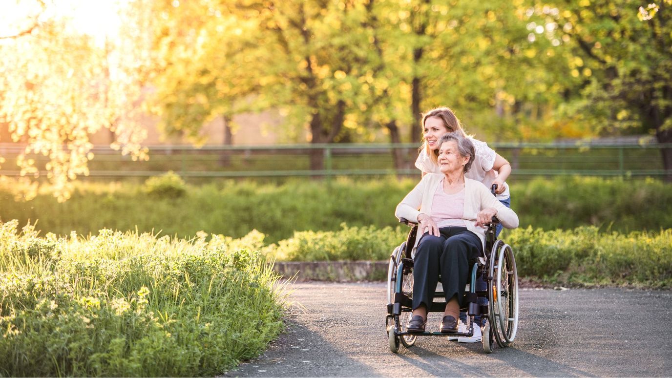 A caregiver pushing a resident in a wheelchair outdoors.