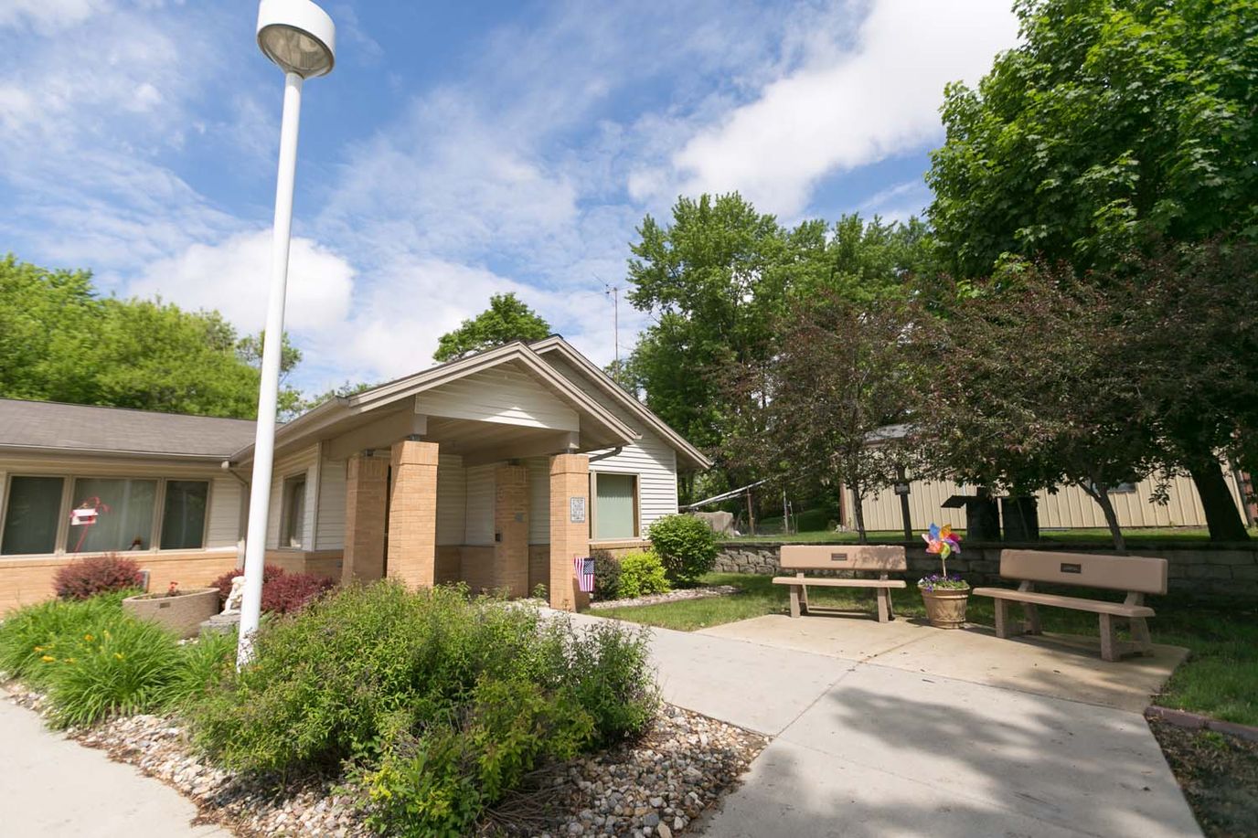 Exterior view of a senior living facility with benches and gardens