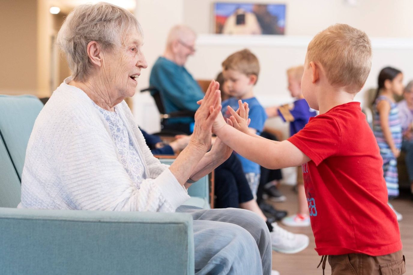 An elderly woman engaging with a young boy in a common area