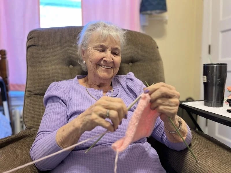 Resident knitting in a cozy chair