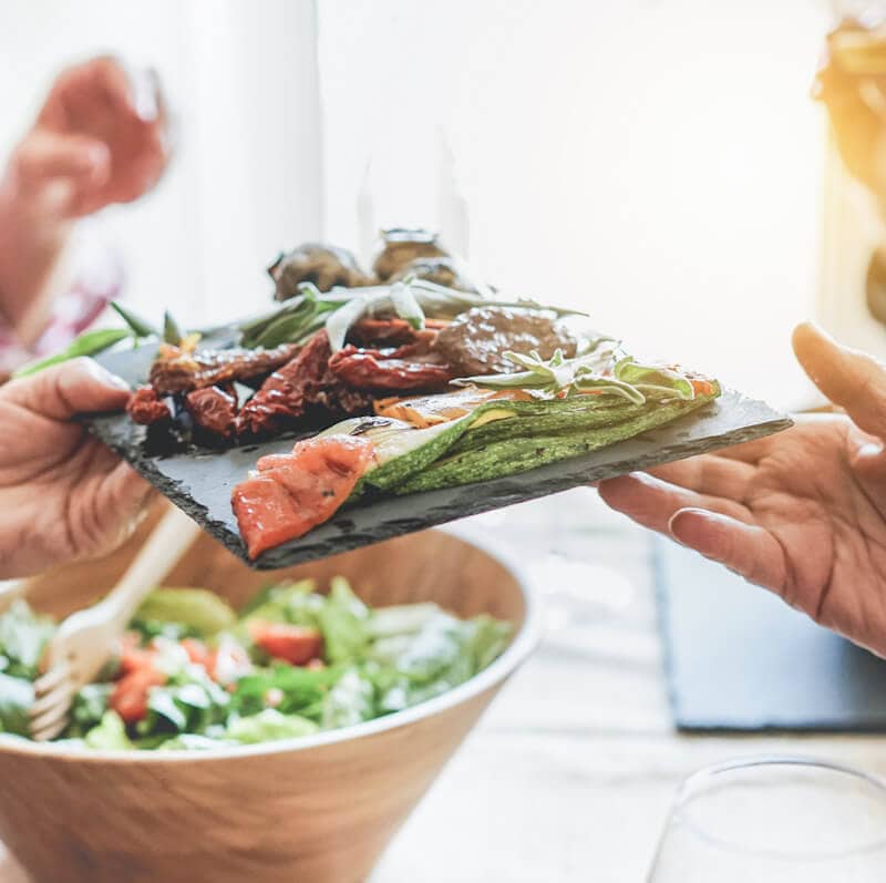 Hands exchanging a plate of food in a dining area