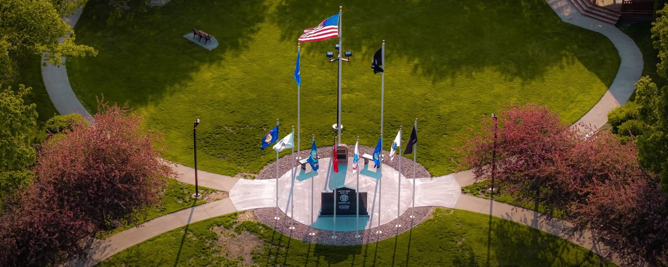 Harmony Place, assisted living in Harmony, MN — Memorial plaza with flags and vibrant landscaping