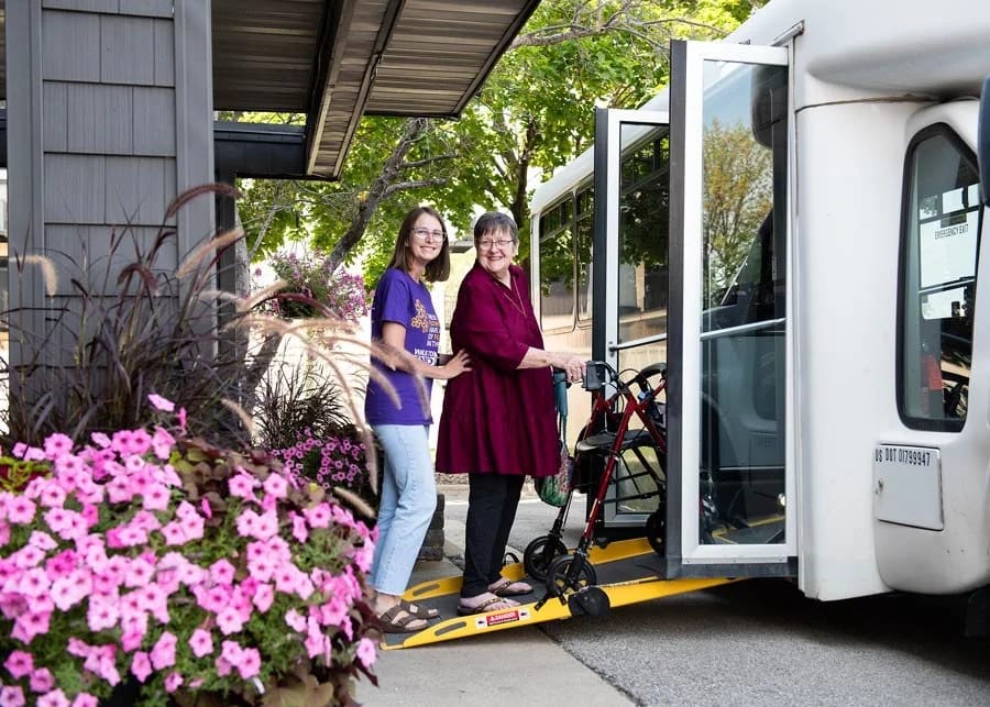 Resident boarding a facility transport vehicle with staff assistance