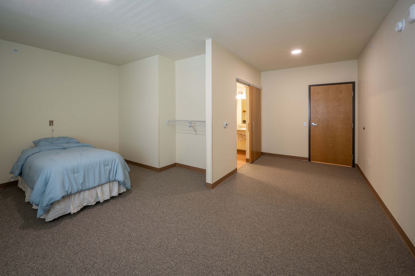 Single resident room with a bed and bathroom door