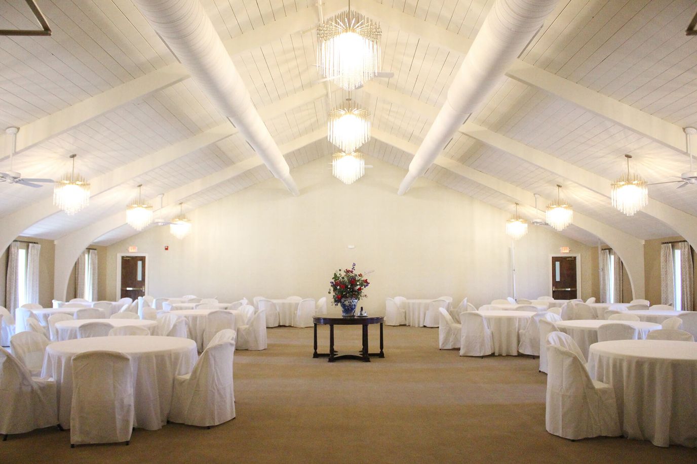 Spacious banquet hall with round tables and floral centerpiece