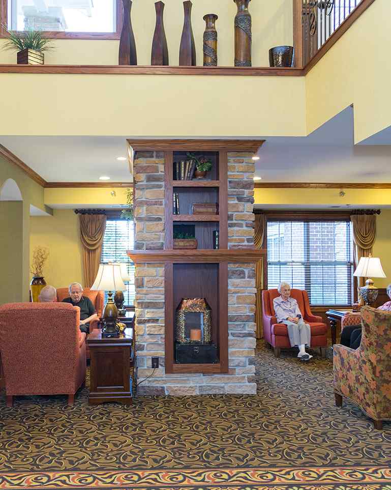 Residents relaxing in a cozy common area with a fireplace