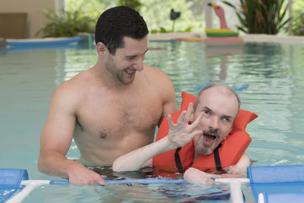 Swimming pool activity with a caregiver and resident.