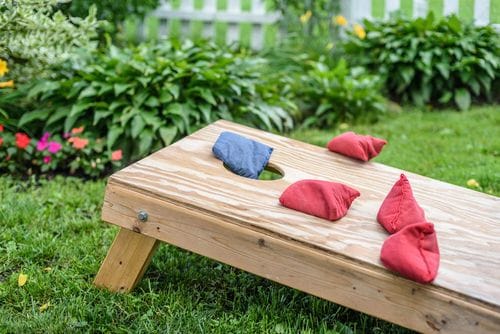 Outdoor cornhole game setup in a garden