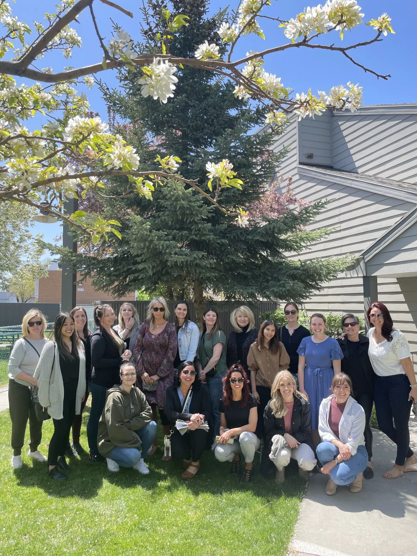 Group of staff members gathered outdoors by the tree.