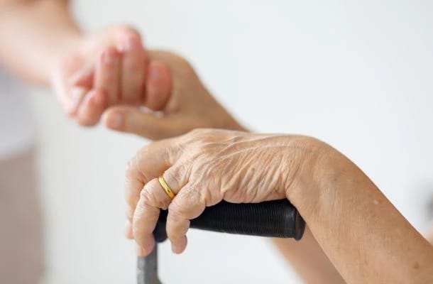 Close-up of elderly hands with a caregiver's hand