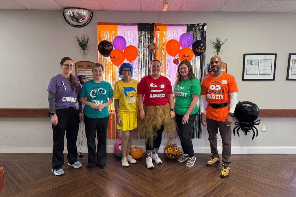 Staff and residents in Halloween costumes with decorations