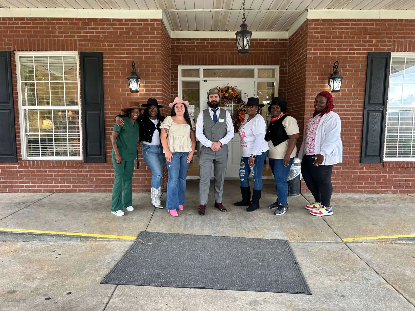 Staff and residents posing in front of the facility entrance