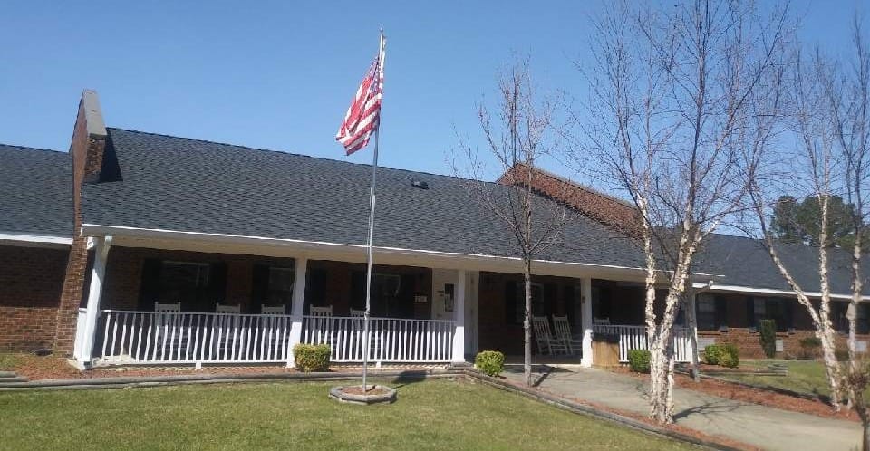 Exterior view of Goldsboro Assisted Living building with flag