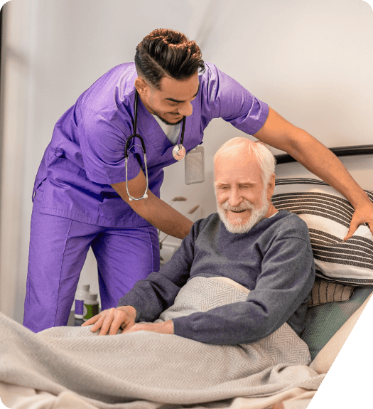 Healthcare worker assisting a smiling resident in bed.