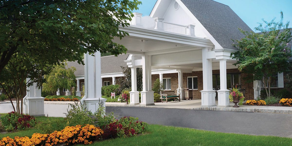 Exterior view of a senior living facility entrance with flowers