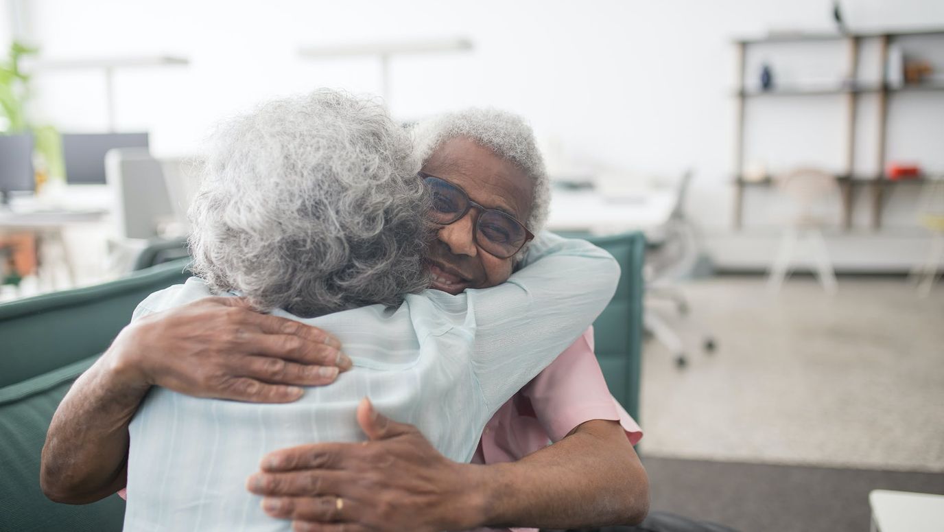Two senior residents embracing in a common area