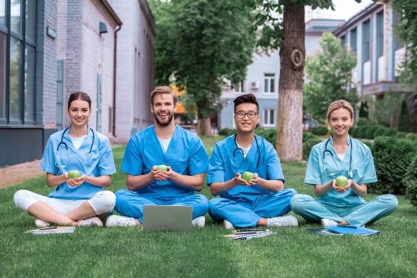 Healthcare staff holding apples in a grassy area