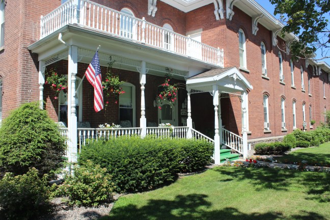 Exterior view of a senior living facility with a porch and garden