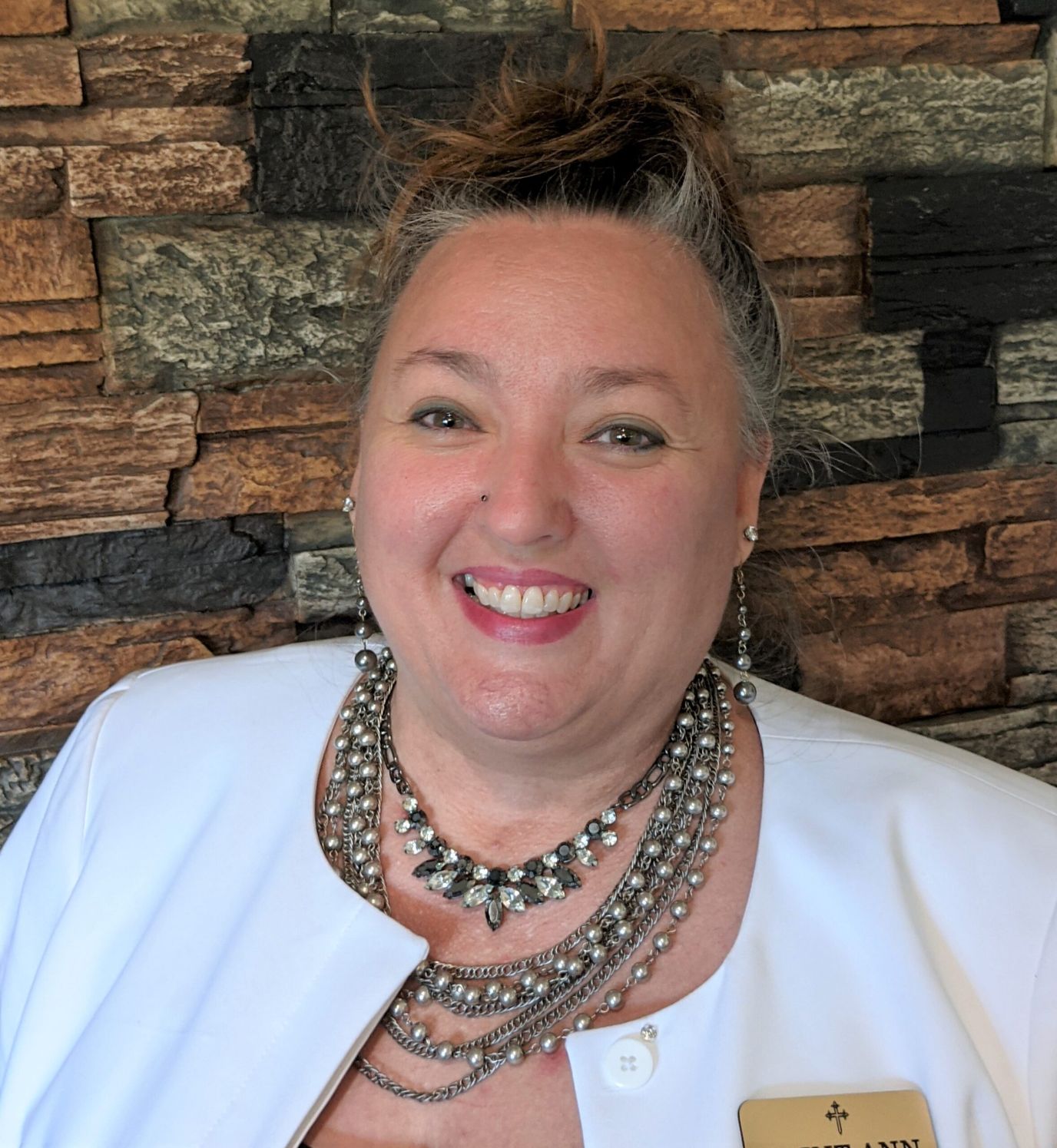 Staff member smiling in front of a stone wall