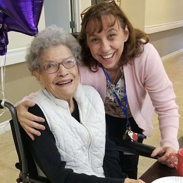 A resident and staff member smiling together