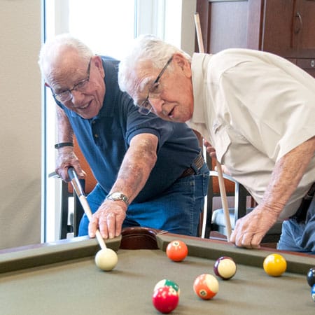 Residents enjoying a game of pool in an activity room.