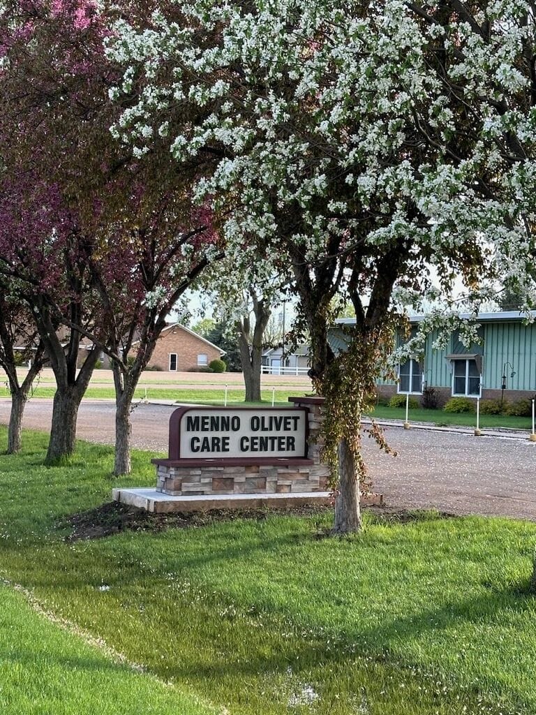 Sign for Menno Olivet Care Center under blooming trees