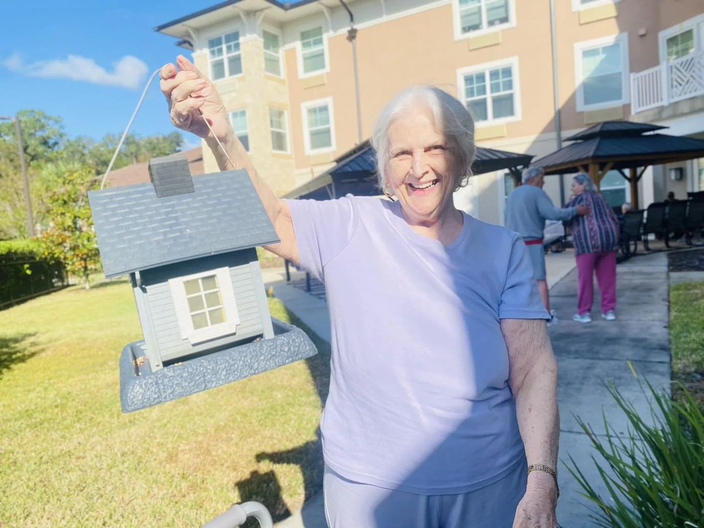 Senior resident displaying a birdhouse outdoors