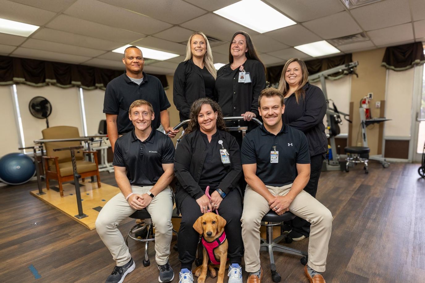 Staff members posing with a therapy dog in the facility