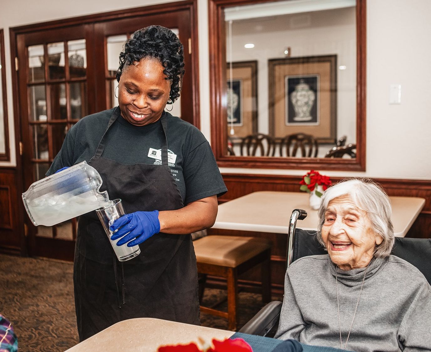 Staff serving a drink to a smiling resident