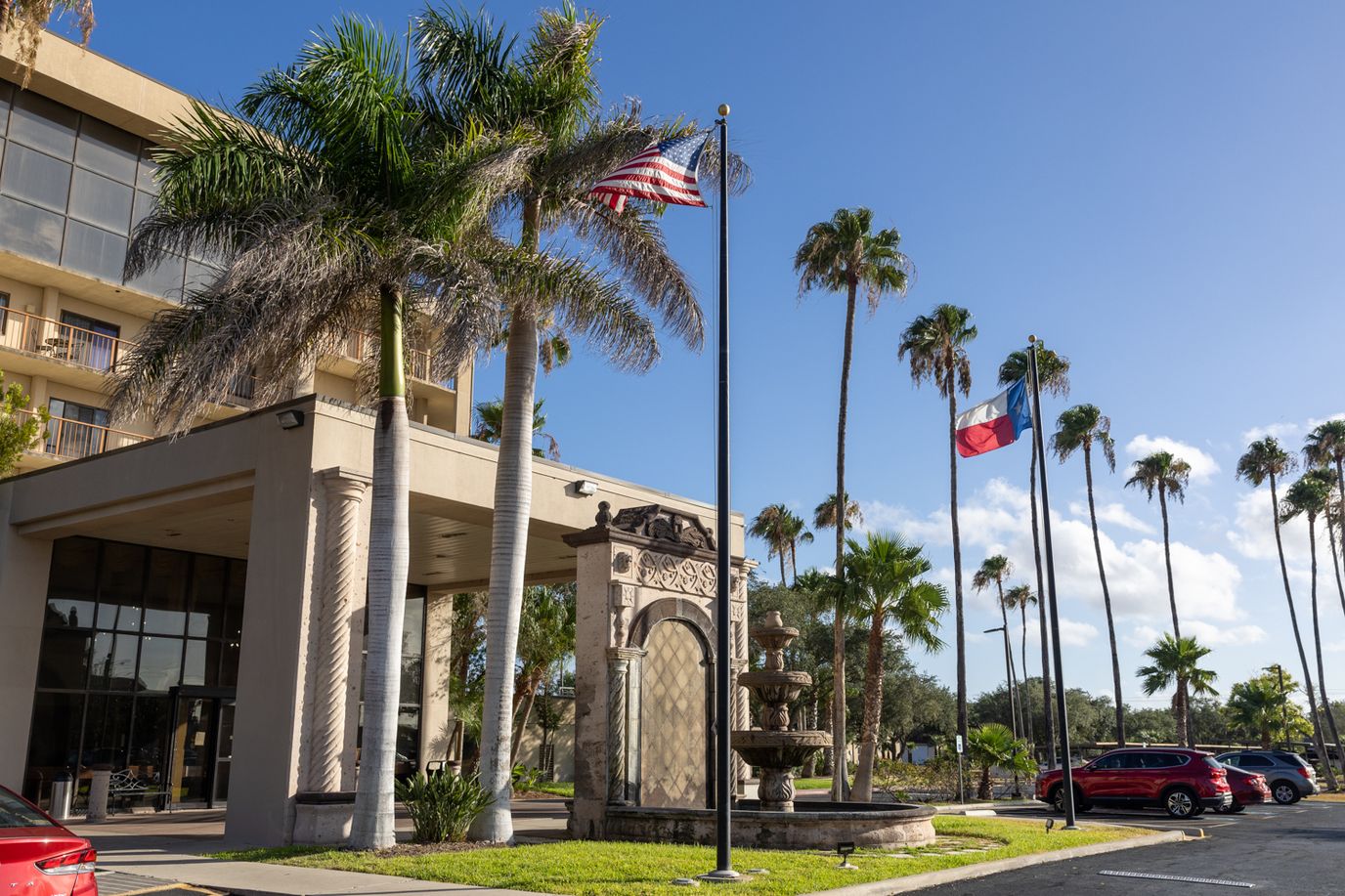 Exterior view of the facility with palm trees and flags