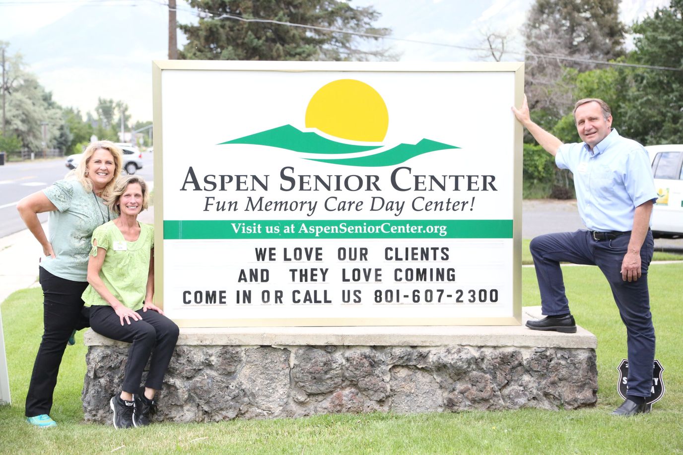Staff members posing by the facility sign