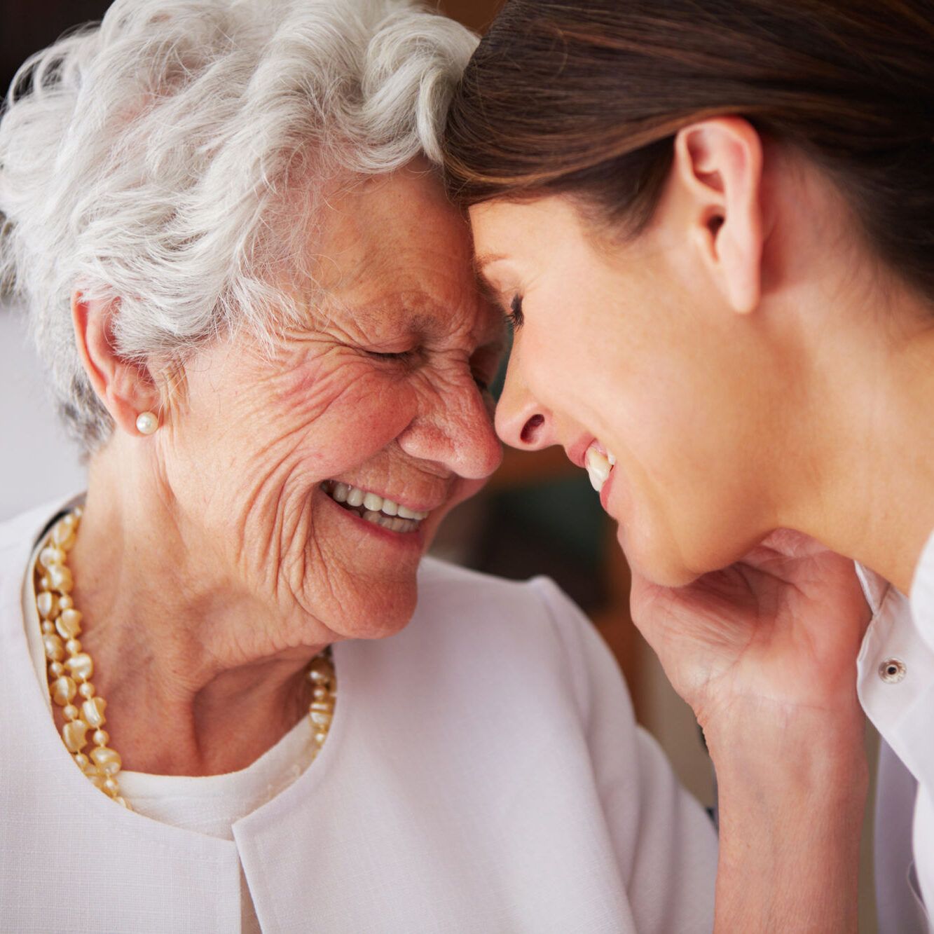 Elderly woman and caregiver sharing a joyful moment.