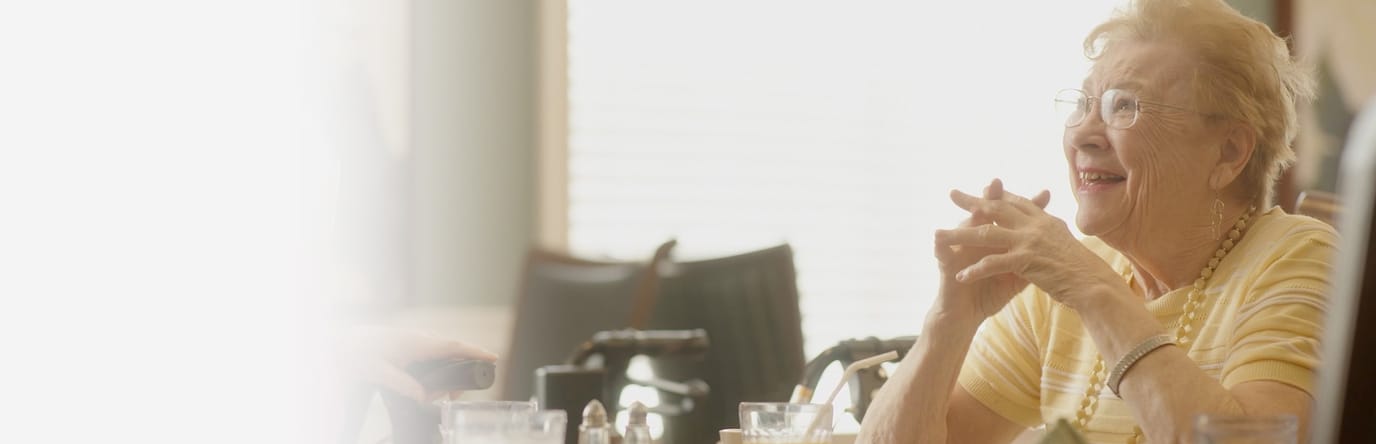 A smiling senior resident in a dining area