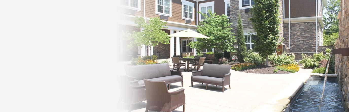 Outdoor seating area with greenery and water feature.
