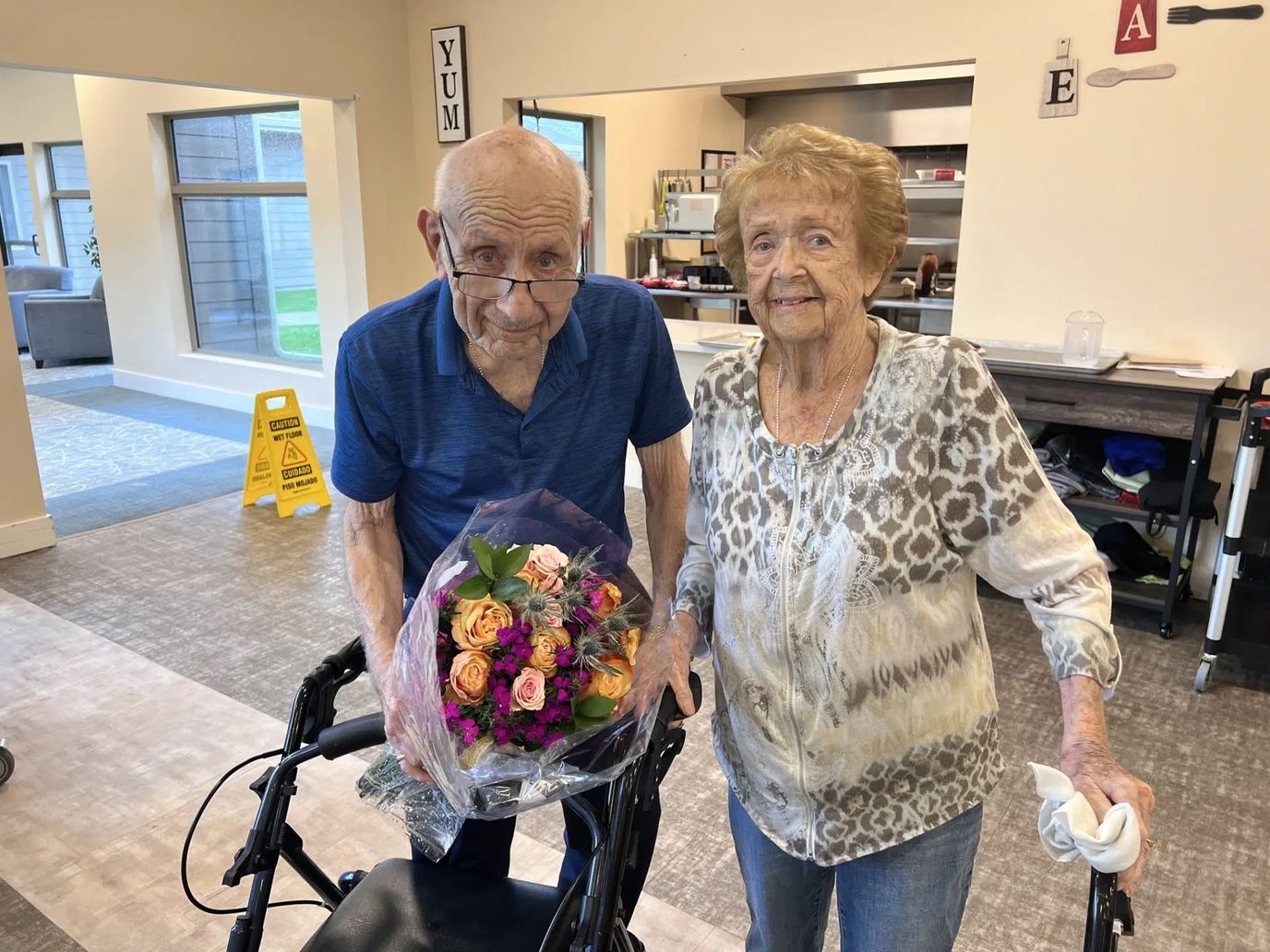 Two residents smiling with a bouquet of flowers in a common area