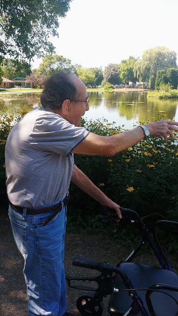 Cahoots Adult Day Service LLC, adult day care in Waupaca, WI — Senior man pointing towards a pond with flowers