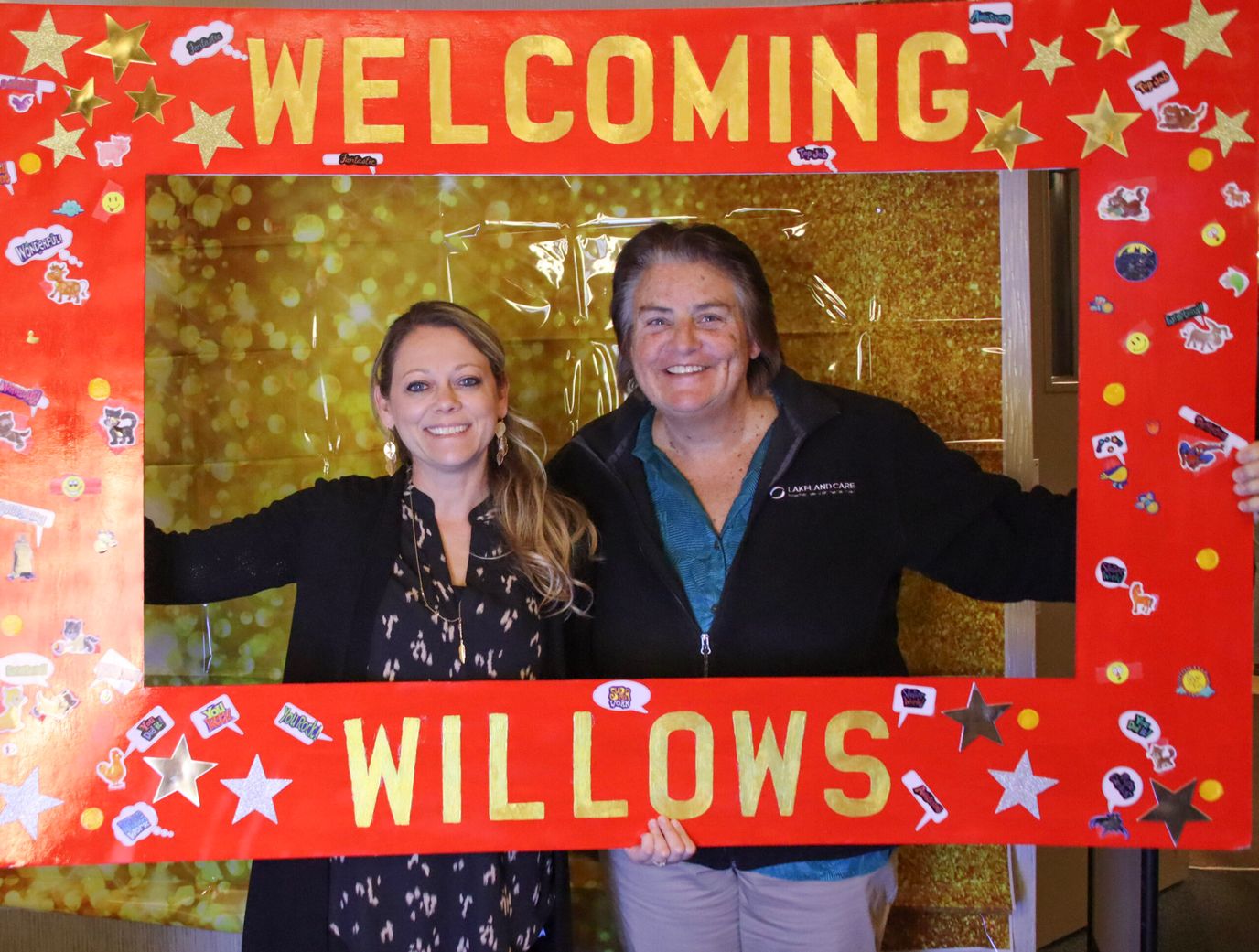 Two staff members posing with a decorated frame
