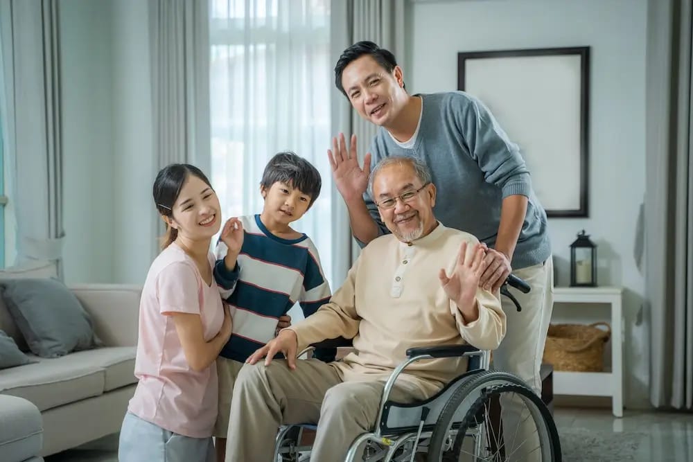 A family visiting a senior in a wheelchair inside a living room