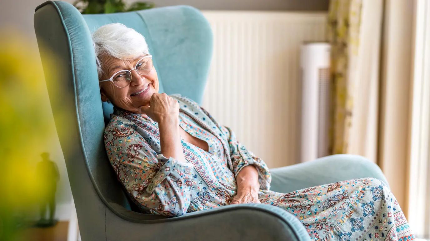 Older woman smiling in a cozy chair indoors