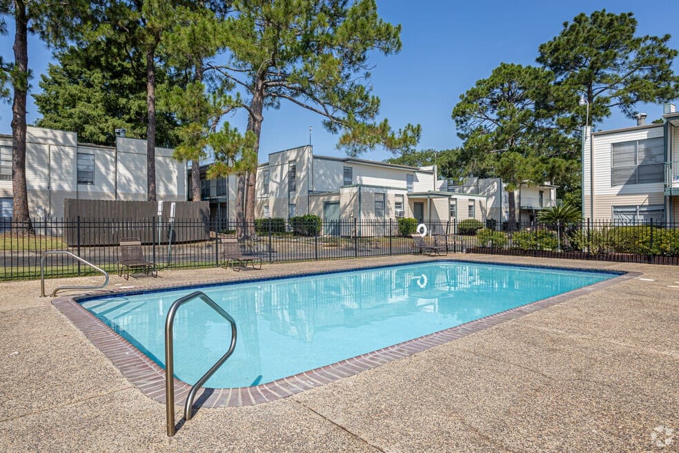 Outdoor pool area surrounded by trees and buildings