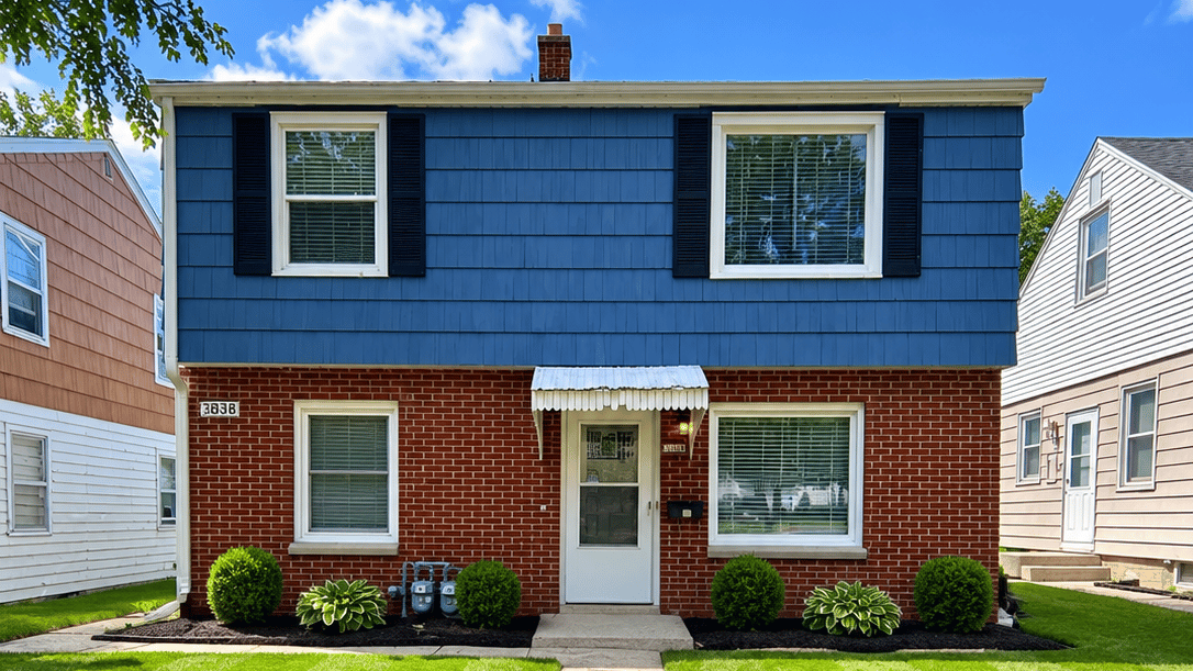 Exterior view of a blue and brick building with shrubs