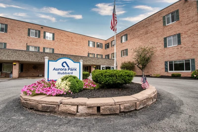 Exterior view of Aurora Park nursing facility with a sign