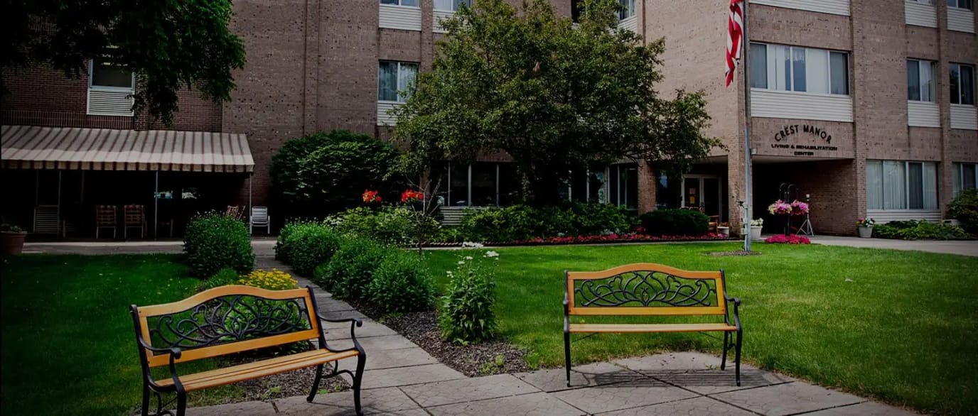 Exterior view of Crest Manor with benches and gardens